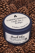 Beach Vibes scented candle in blue tin on pinecone background