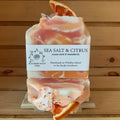 Sea Salt and Citrus handmade soap bars with orange and cream swirl design and dried orange slice on a wooden display