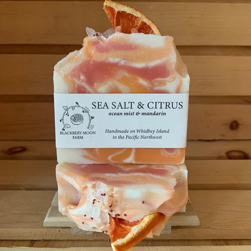 Sea Salt and Citrus handmade soap bars with orange and cream swirl design and dried orange slice on a wooden display
