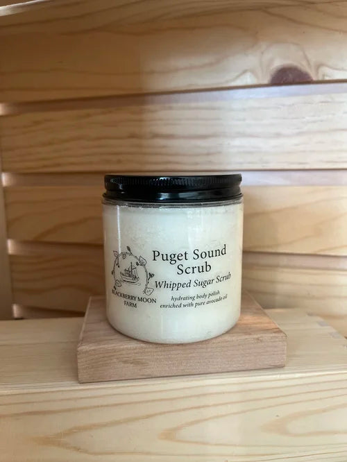 Puget Sound whipped sugar scrub in clear jar with black lid on wooden blocks 