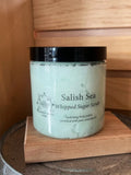 Salish Sea whipped sugar scrub in clear jar with black lid on wooden surface