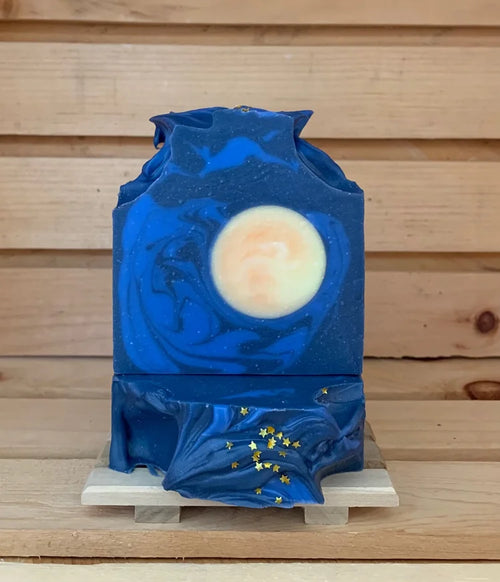 Handmade blue soap bars with moon and stars design on a wooden display