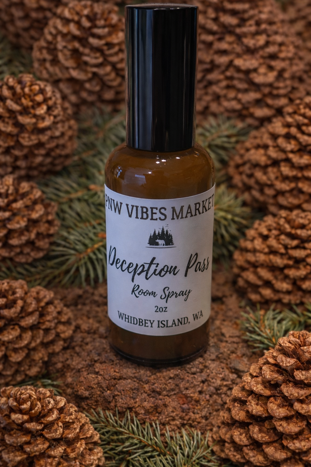 Deception Pass room spray in amber bottle with black spray top on pinecone background.