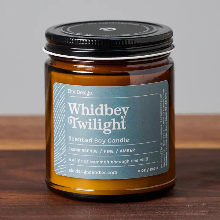 Whidbey Twilight scented soy candle in amber glass jar with black lid on wood surface