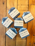 Handmade charcoal and tea tree soap bars arranged on wooden surface