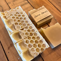 Handmade milk and honey soap bars on wooden surface with soap box