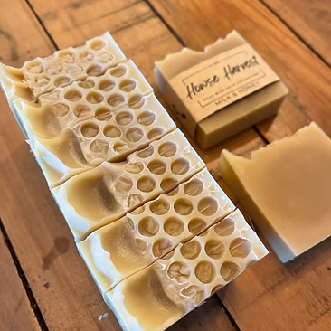 Handmade milk and honey soap bars on wooden surface with soap box