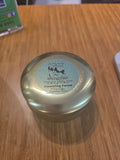 On the Rocks Apothecary Flowering Forest candle in gold tin on wood surface.