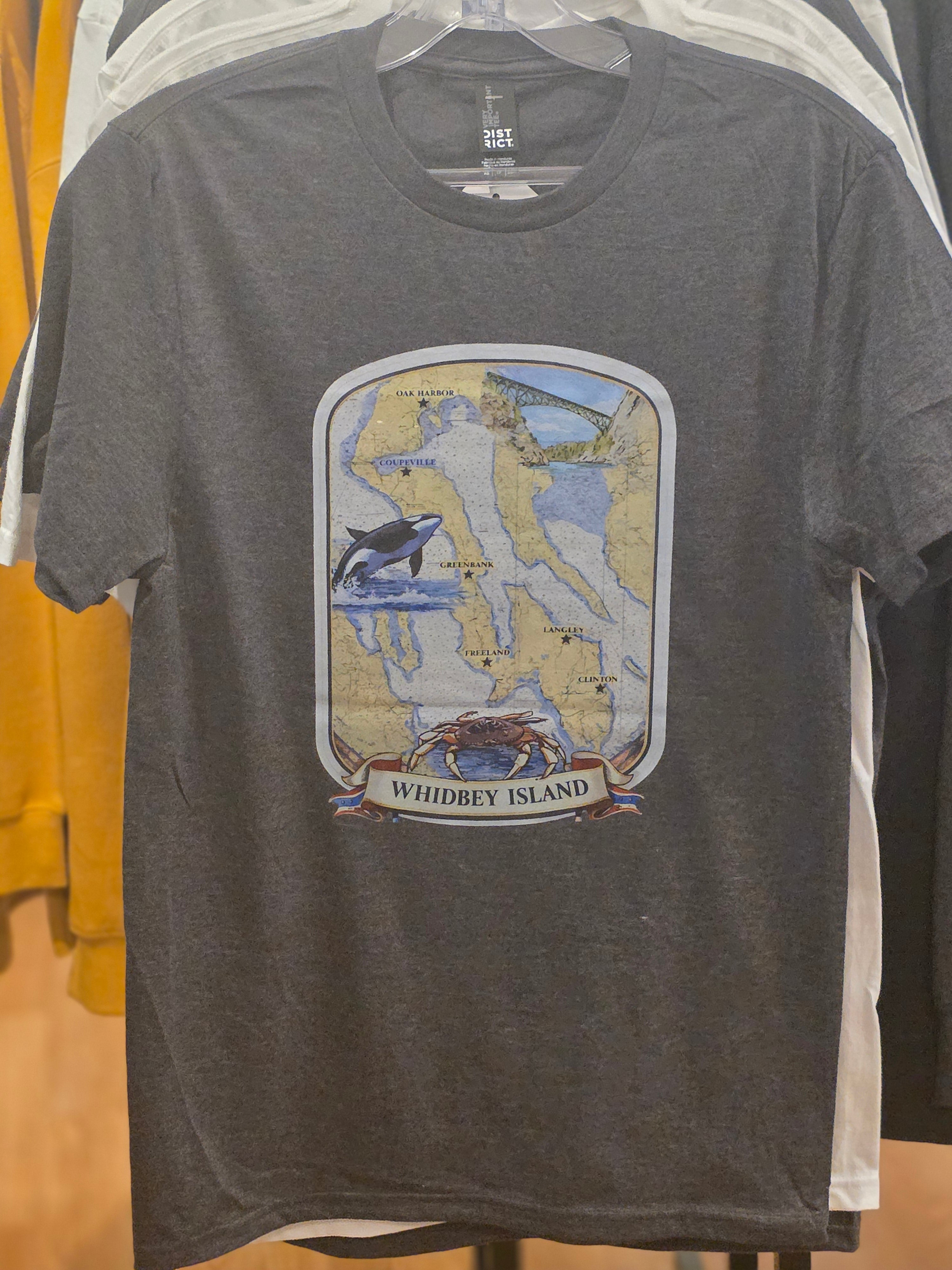 Gray T-shirt with illustrated map of Whidbey Island featuring an orca whale, crab, and Deception Pass Bridge with Whidbey Island text.